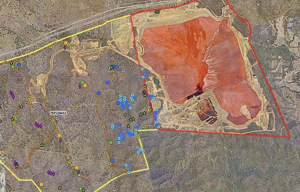 Aerial view of construction vehicles operating within a cleared area near Gladstone’s alumina refinery, showing active borrow pits, haul roads, and stockpiles surrounded by native vegetation.